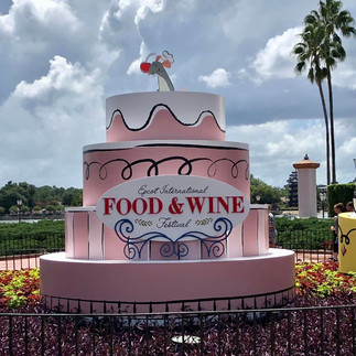 Food and Wine at Epcot; A large pink cake with a food and wine sign