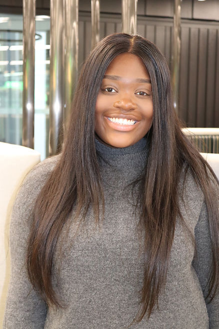 Smiling woman with long brown hair, wearing a grey sweater. Future Frontiers.