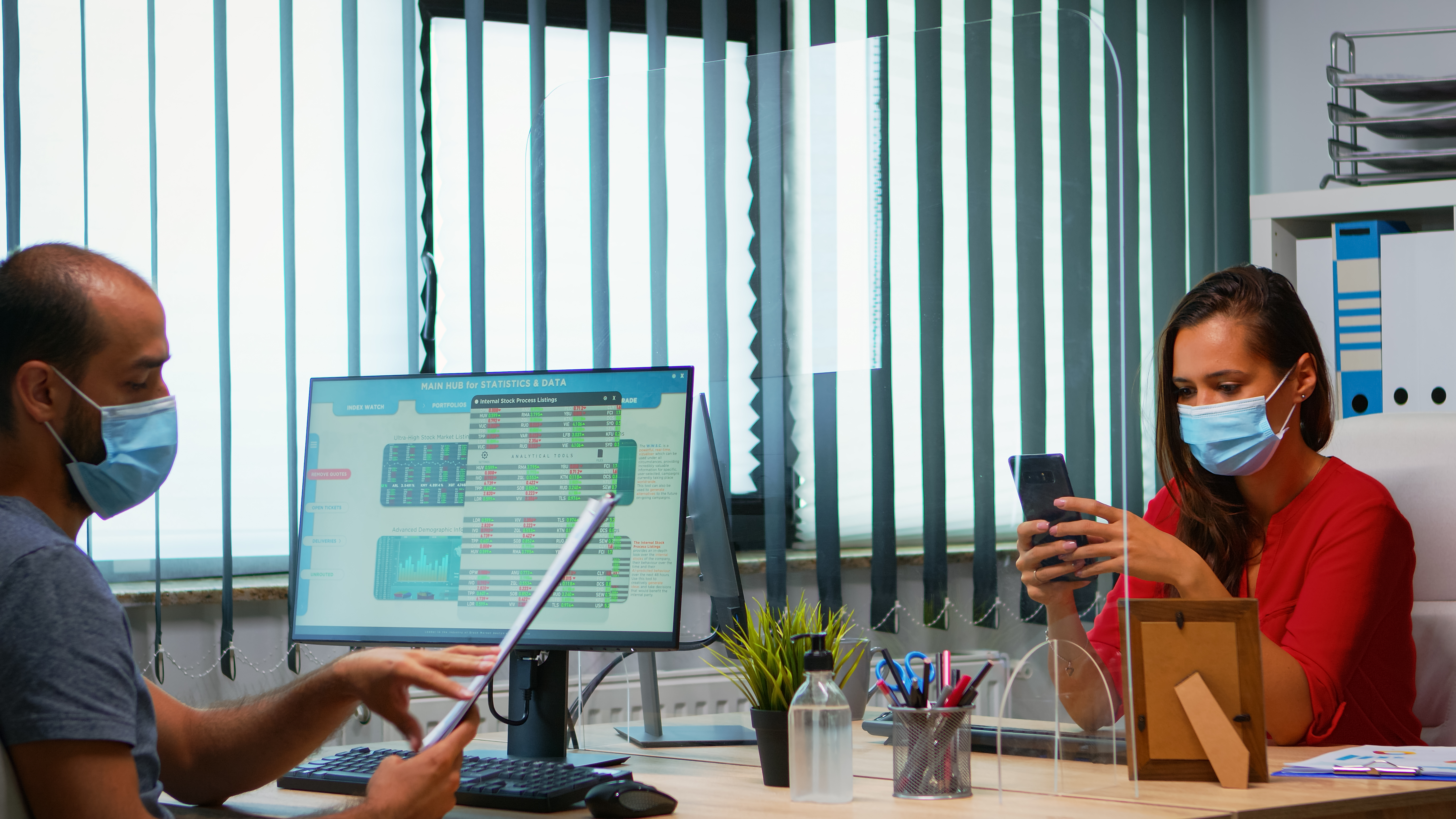 woman-with-protective-mask-typing-phone-while-colleague-working-using-clipboard-respecting