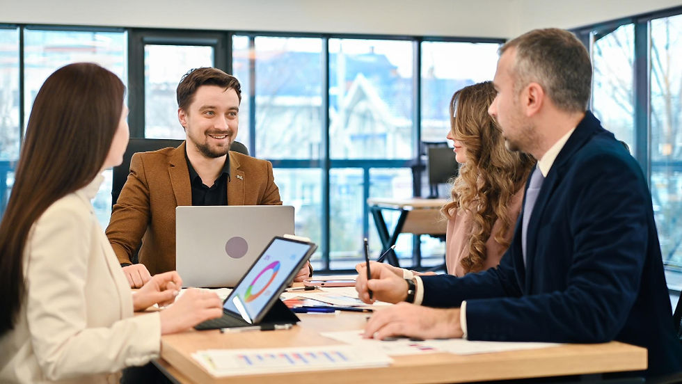 Four diverse business professionals discussing data on a tablet in an office.