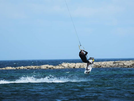 Person kitesurfing over ocean waves