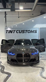 Dark grey BMW with doors open inside TINTCUSTOMS shop.