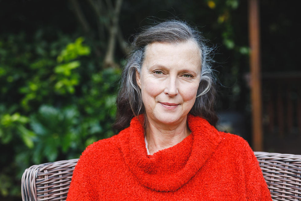 Smiling woman with graying hair wearing a red sweater outdoors