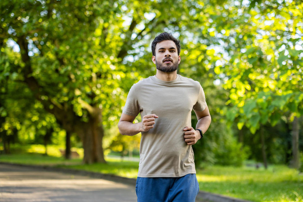 Bearded man jogging in park, wearing earbuds and smartwatch.