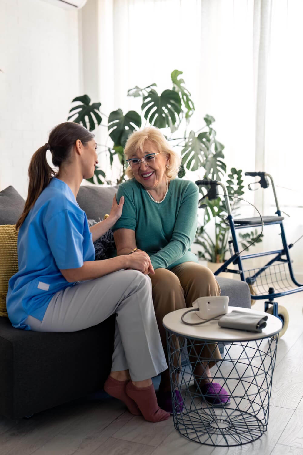 Caregiver comforts a senior woman while sitting; medical assistance and support