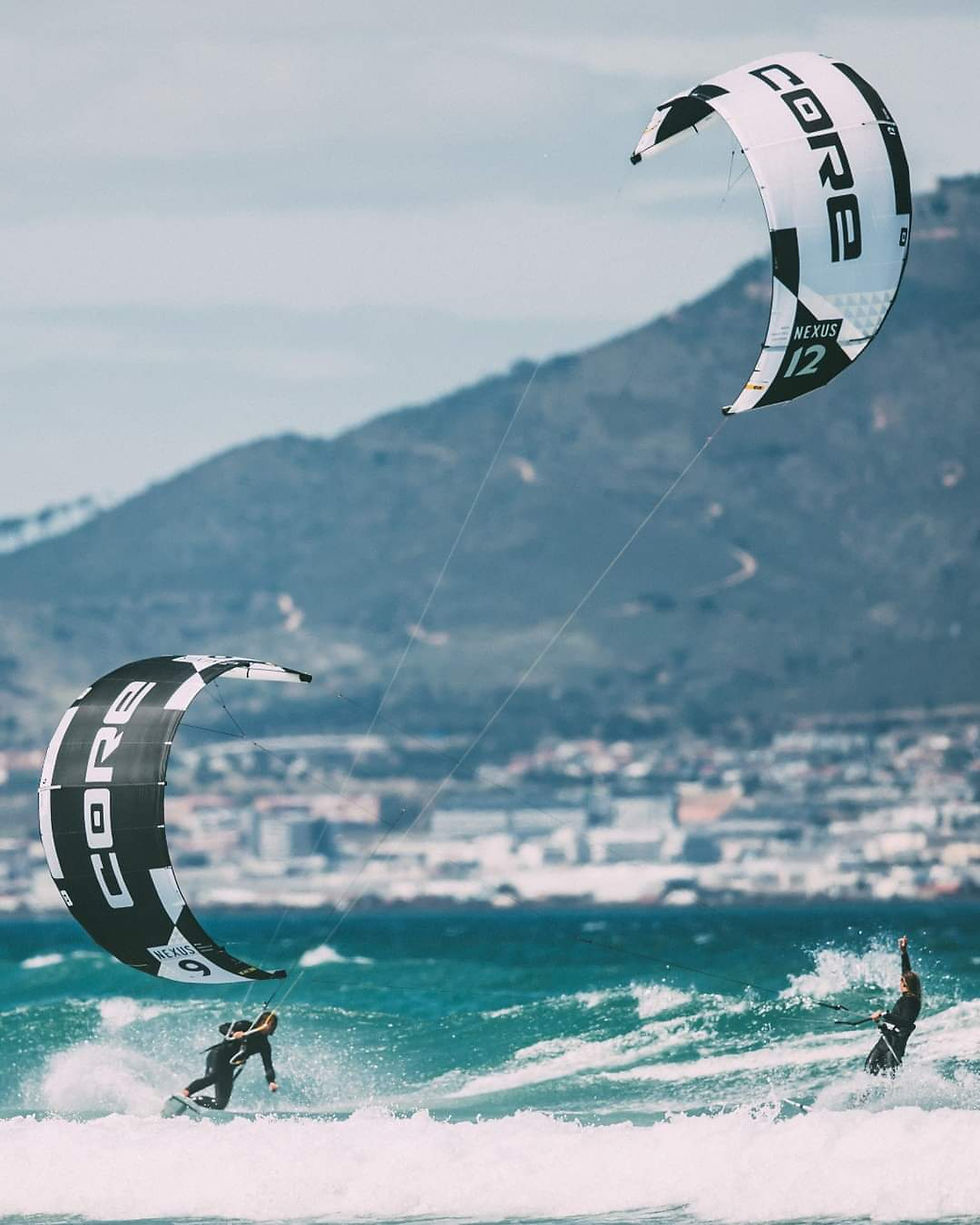 Kitesurfers ride ocean waves near mountains
