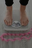 Person's feet on weight scale, measuring weight indoors, health and wellness.