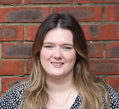 Smiling woman, headshot, against brick wall