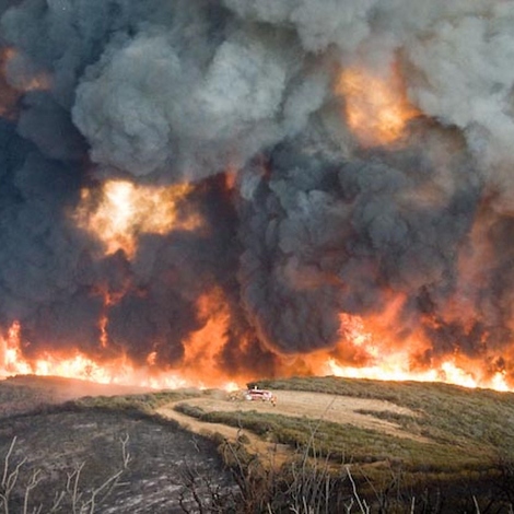 Large fire engulfing the landscape with billowing smoke and flames rising