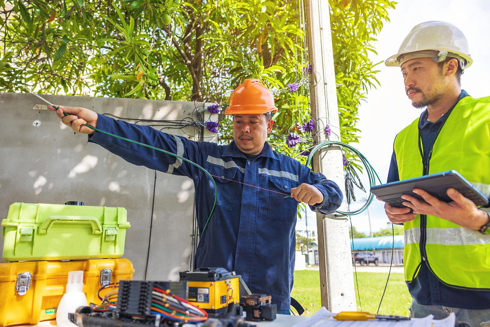Two Asian technicians working on power lines, one holding a wire.