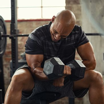Man lifting dumbbells in gym; workout, strength training, and exercise focus.