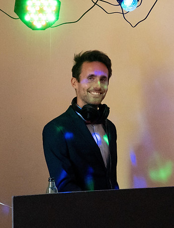 Young man in a suit is discjocking on a wedding party