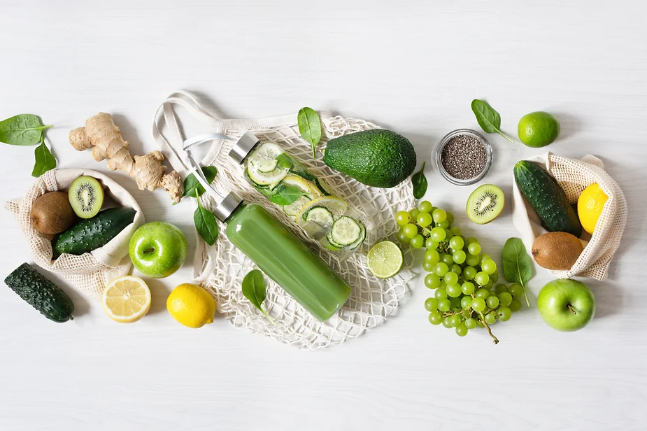 Fresh green ingredients and colorful fruits and vegetables spilling out of a reusable grocery bag