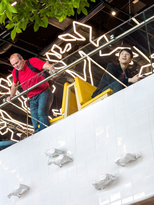 People viewing wall installation from upper level, airport setting