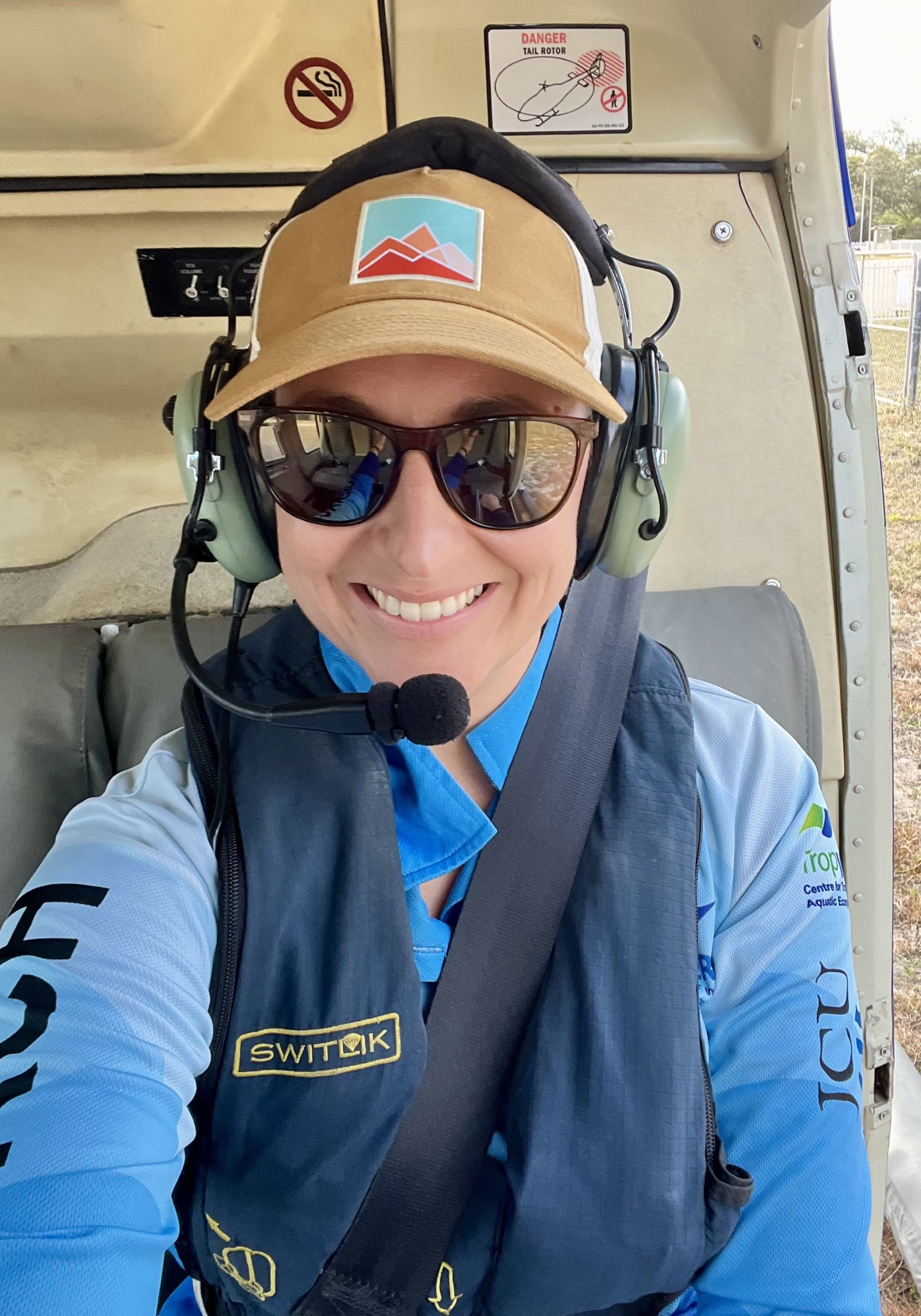 A person sitting in a helicopter, wearing sunglasses and a headset