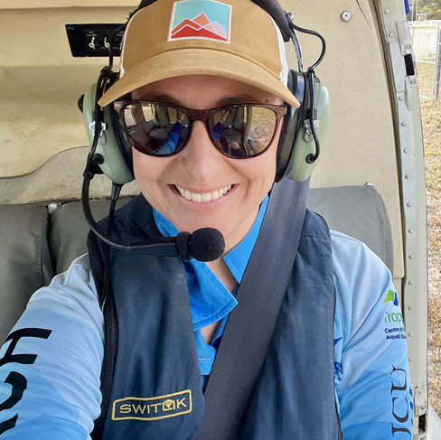 A person sitting in a helicopter, wearing sunglasses and a headset