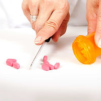 Pharmacist cutting pills