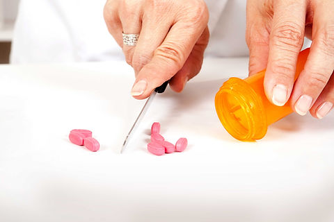 Pharmacist cutting pills