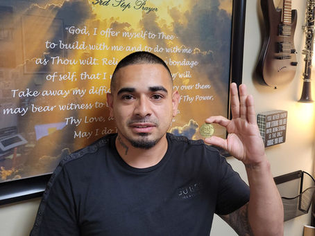 Miguel holding up his alumni chip from Dallas 24 Hour Club