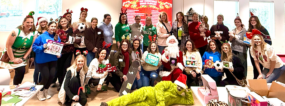 A group of volunteers dressed in festive holiday attire posing before the Resident Toy Market