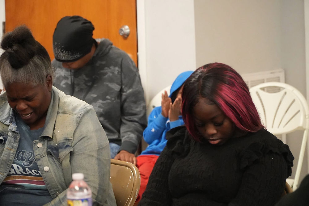 Young adults and children with bowed heads in a moment of reflection