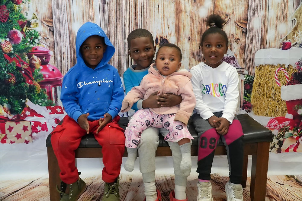 Four children posing in front of a Christmas backdrop