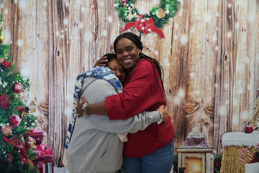 Two smiling women hugging at a Christmas event