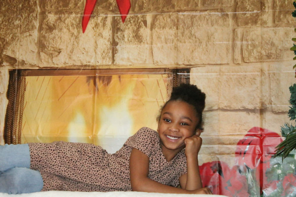 Happy girl lying by a festive fireplace backdrop