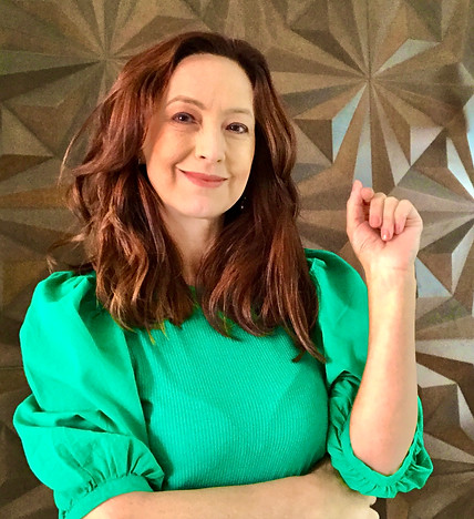 Psicóloga Vilma Napoli, pele branca, cabelos longos e ondulados castanhos. Está usando umcamisa bufante verde. Sorrindo