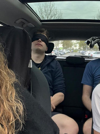 Vier Personen mit Augenbinden sitzen im Auto auf dem Weg zum FangMichDoch Startpunkt