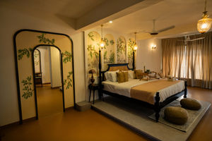 Elegant King Suite room at Villa Vara showcasing botanical arch murals, four-poster bed, cozy seating poufs, and soft natural lighting