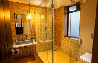 Modern bathroom with glass shower and warm-toned tiles in the Paradise Suite.