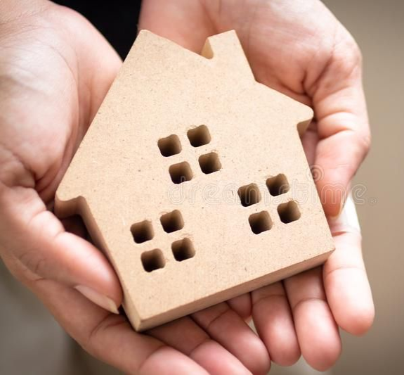 Casa de madeira nas mãos, representando regularização imobiliária simples e segura