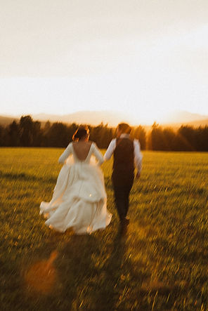 blurry photo of wedding couple running towards sunset in field