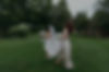Bride walking across lush green lawn with bridesmaid holding her veil during an outdoor Vermont wedding at a New England wedding venue
