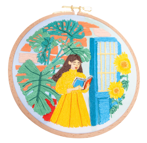 רקמה מודרנית בשילוב צבעים אקרילים. אישה לבושה בצהוב הולכת ברחוב וקוראת ספר. מסביבה נוף אורבני של בניין וצמחים. ברקמה השתמשתי בתך סאטן, תך שרשרת, לייזי דייזי, קשר צרפתי