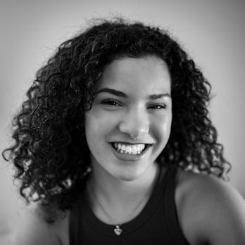 Souriante jeune femme aux cheveux bouclés regarde la camera. Portraits, JRP photographe.