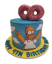 Blue Homer Simpson birthday cake decorated with clouds, large pink donuts on top and personalised yellow birthday board celebrating a 9th birthday.