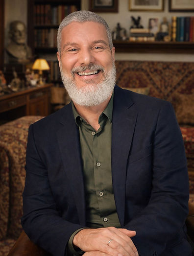 Psicanalista em consultório acolhedor, sorrindo, com livros ao fundo, ambiente de escuta clínica em saúde mental