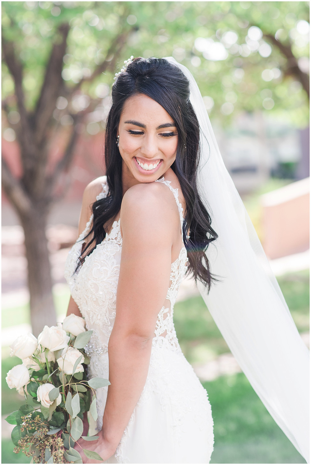 Bride before ceremony with wedding veil and white rose bouquet in white lace wedding dress