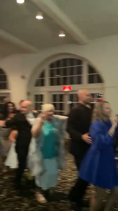Wedding guests dancing in a white room with arched windows and green gobo lighting
