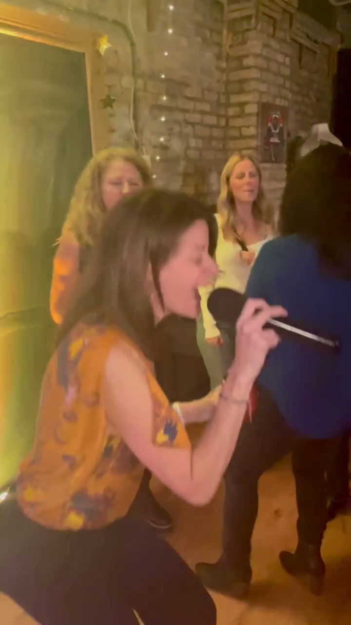 Guests singing karaoke with wireless mics in a brick-walled bar