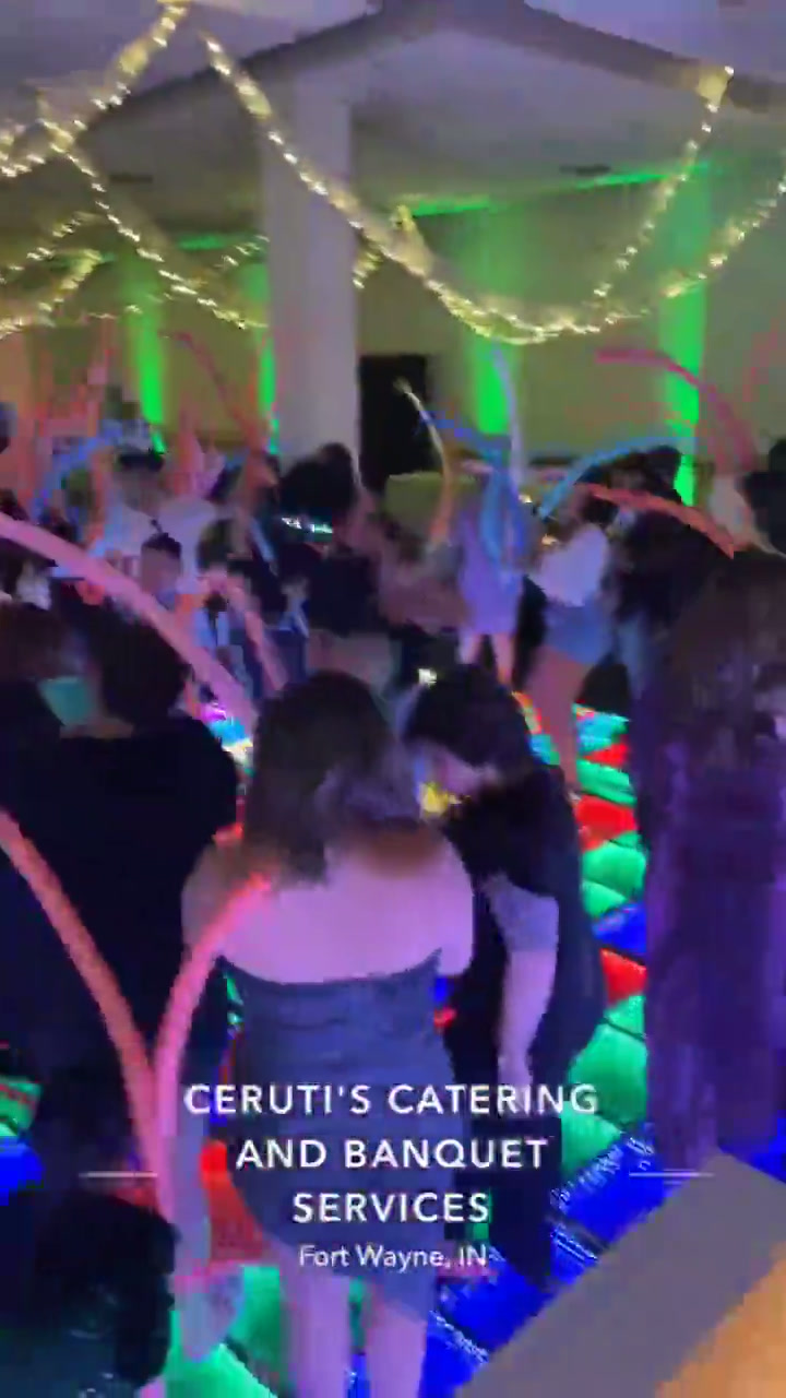 Packed LED dance floor with guests waving glow sticks, Fort Wayne