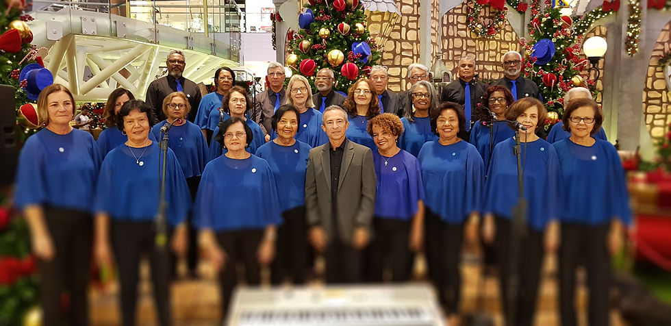 Coral cantando em frente a uma árvore de Natal, pessoas vestindo roupas azuis