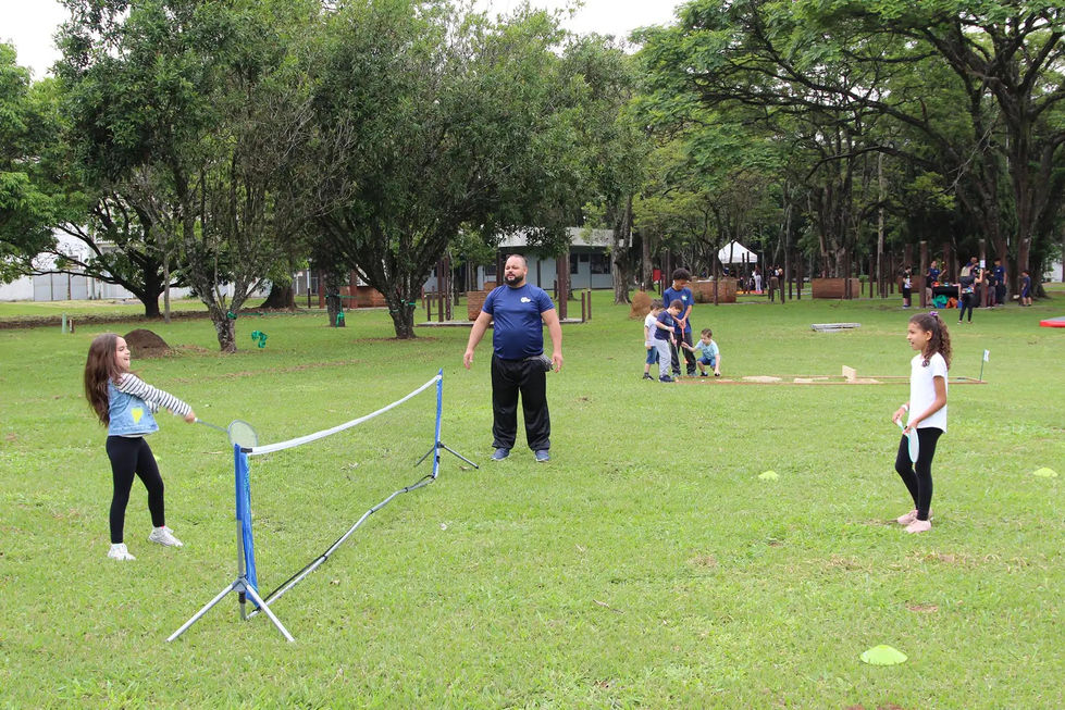 Crianças jogando badminton em quadra adaptada.