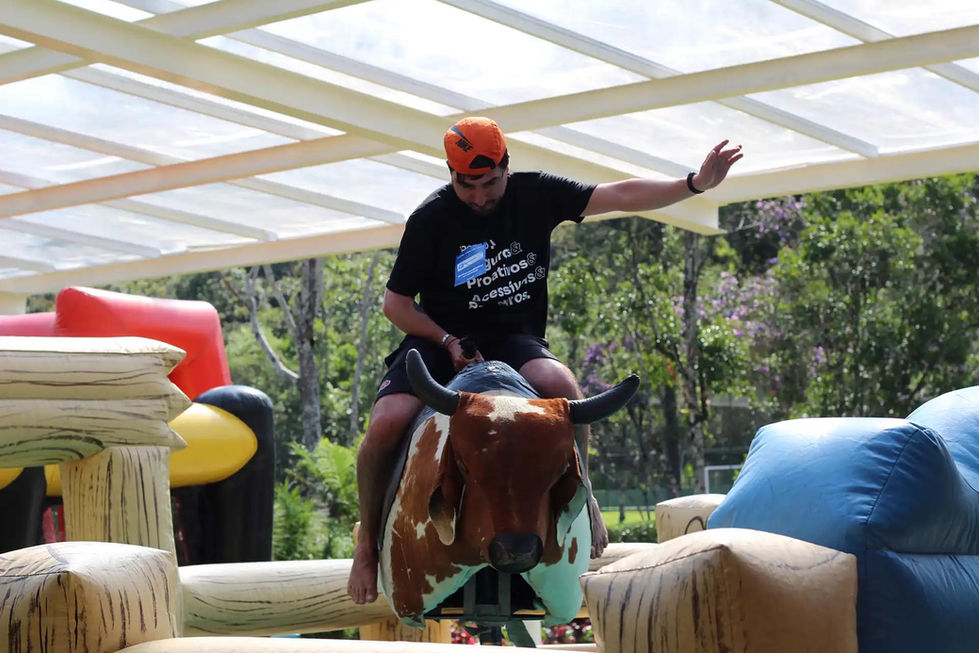 Participante montado em touro mecânico durante festa temática empresarial.