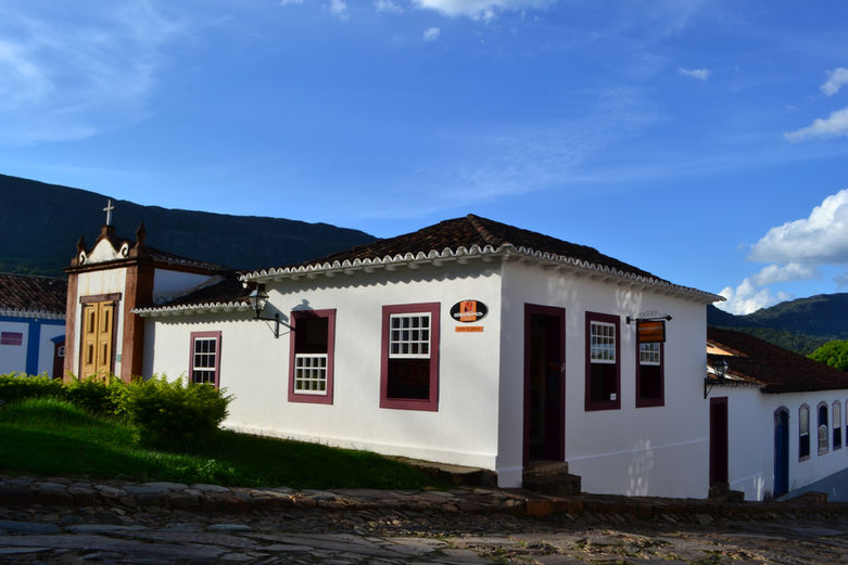 Fachada colonial da Rádio FM Ouro em Ouro Preto sob céu azul.