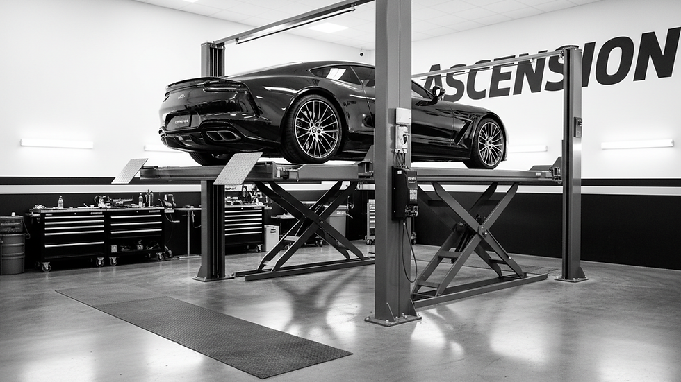 Close-up view of a four-post car lift with a vehicle raised in a professional auto shop