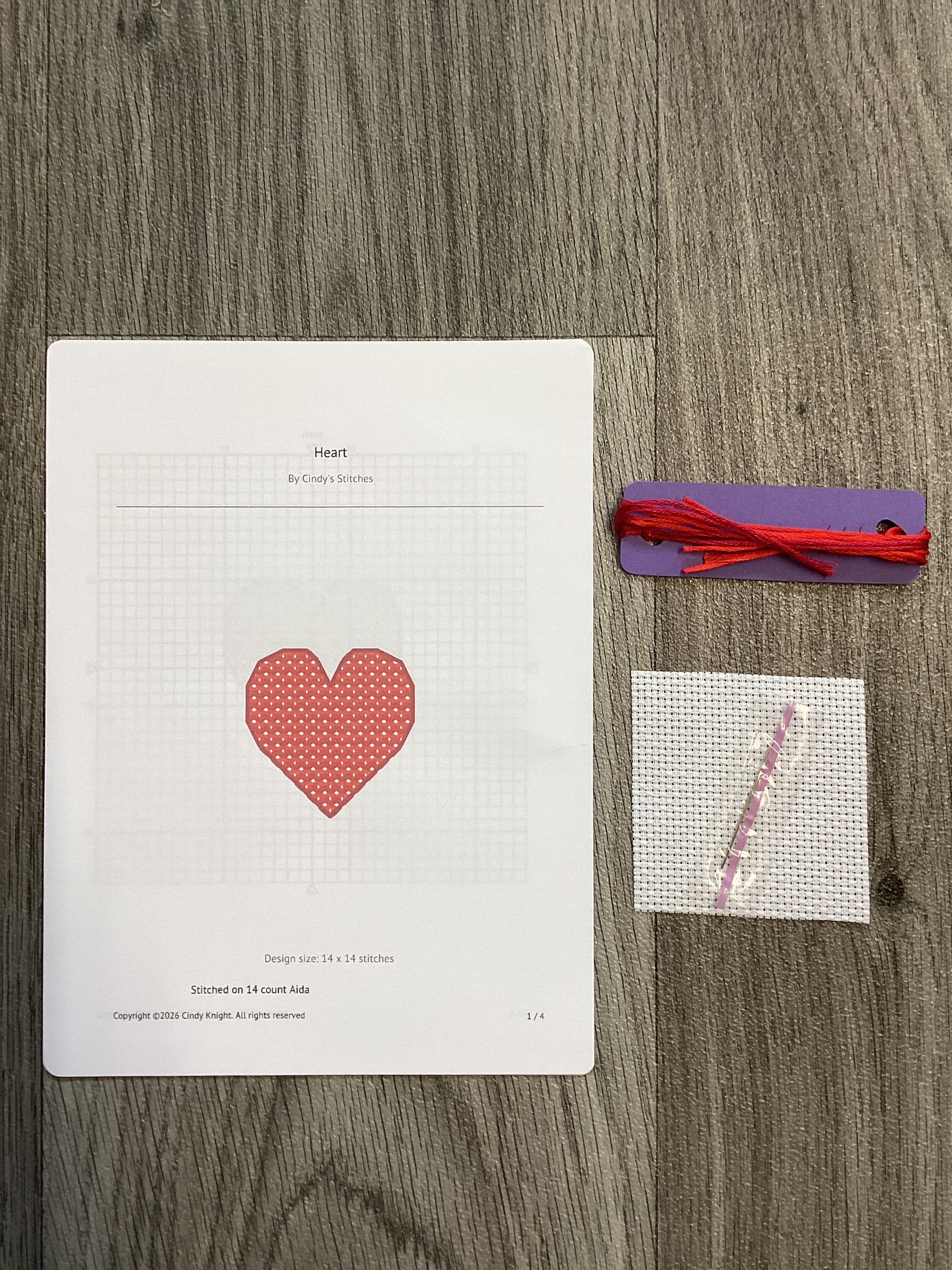Cross stitch kit with heart pattern, fabric, needle, and floss