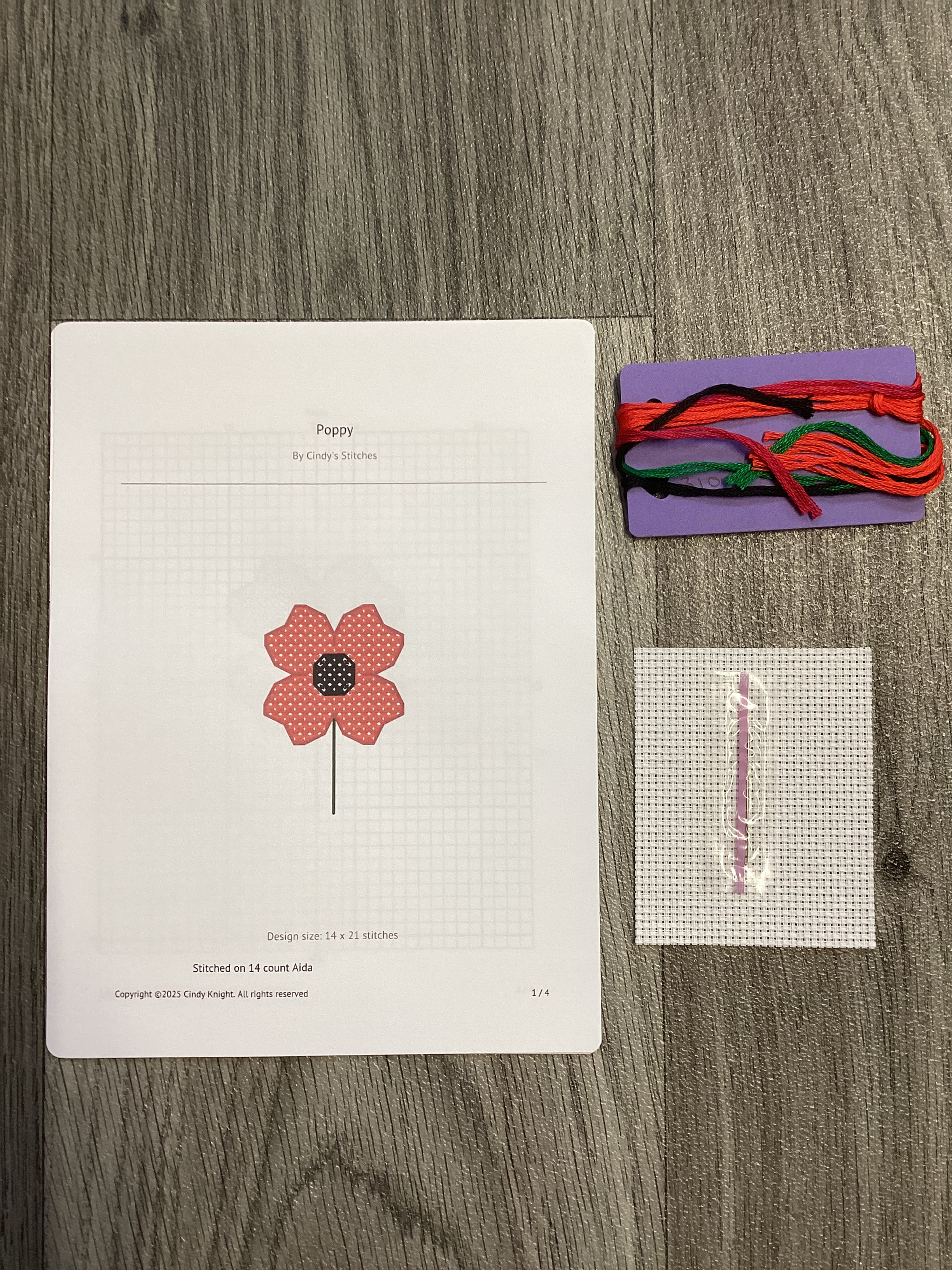 Poppy cross stitch pattern with threads and fabric